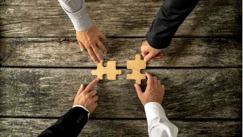 businessmen merging two puzzle pieces depicting merger